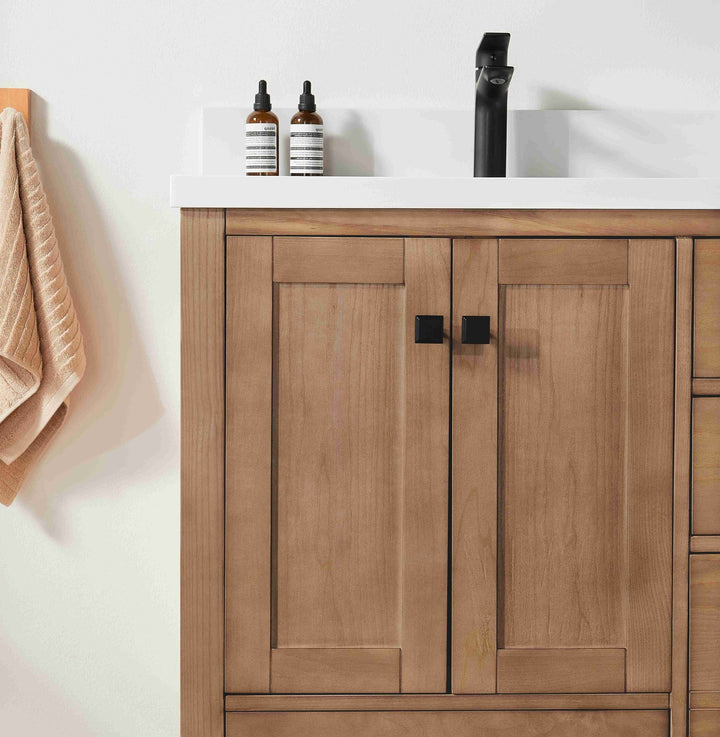 Wooden bathroom vanity with white countertop, towel, and toiletries.
