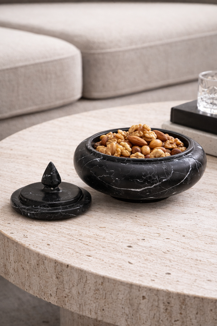 Black marble bowl with nuts on a light wood coffee table