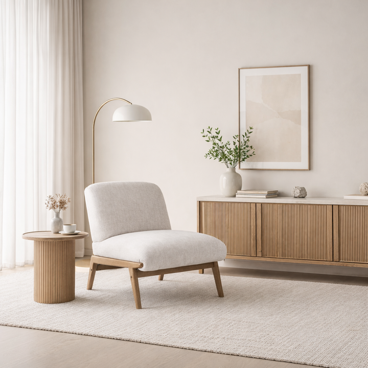 Modern living room with a white armchair, wooden side table, and light-colored walls.
