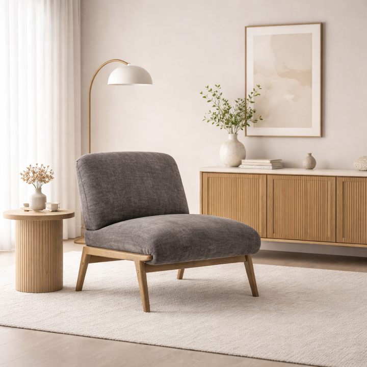 Gray armchair in a modern living room with wooden side table and cabinet.